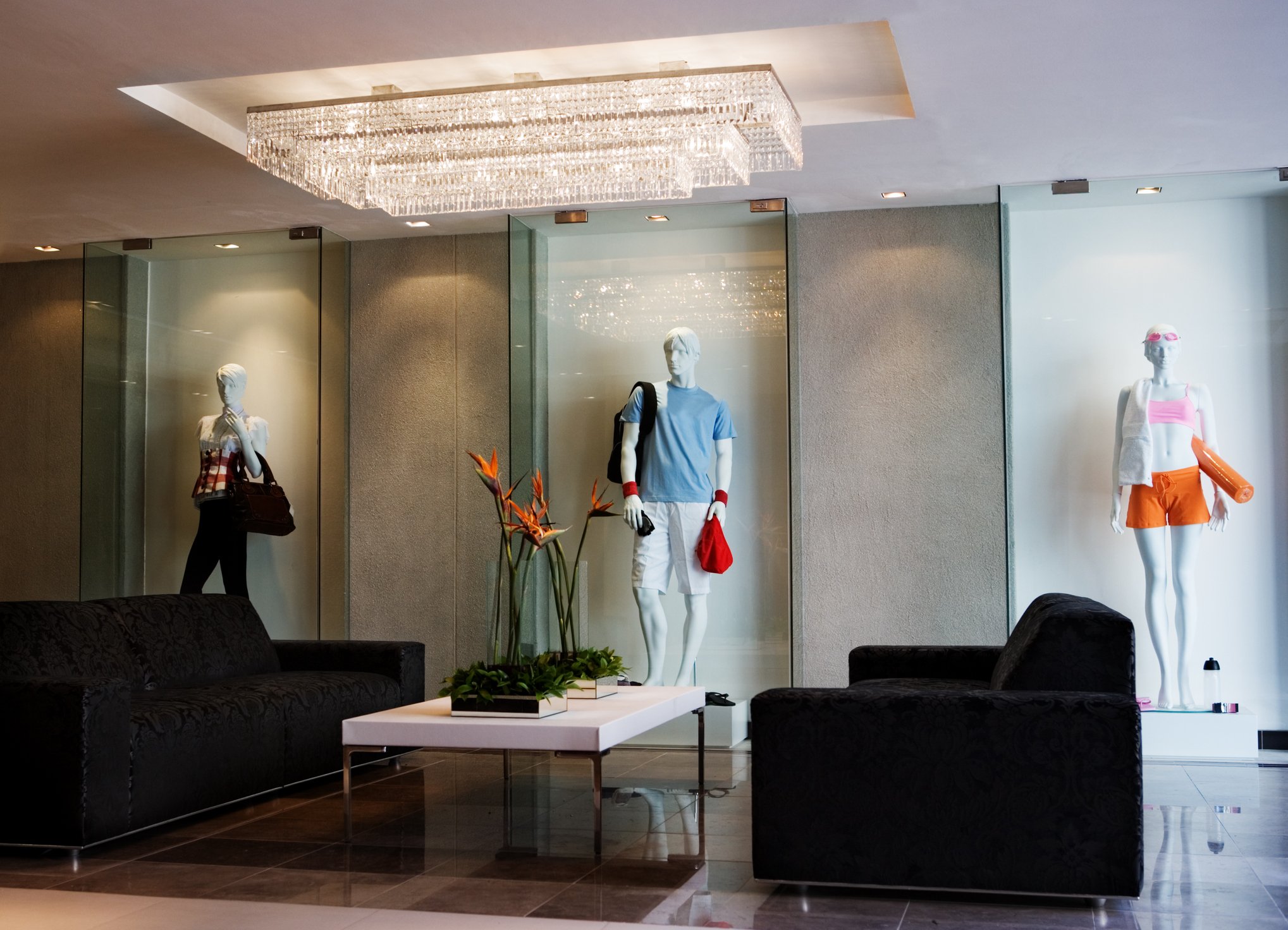 An empty retail space with mannequins and couches.