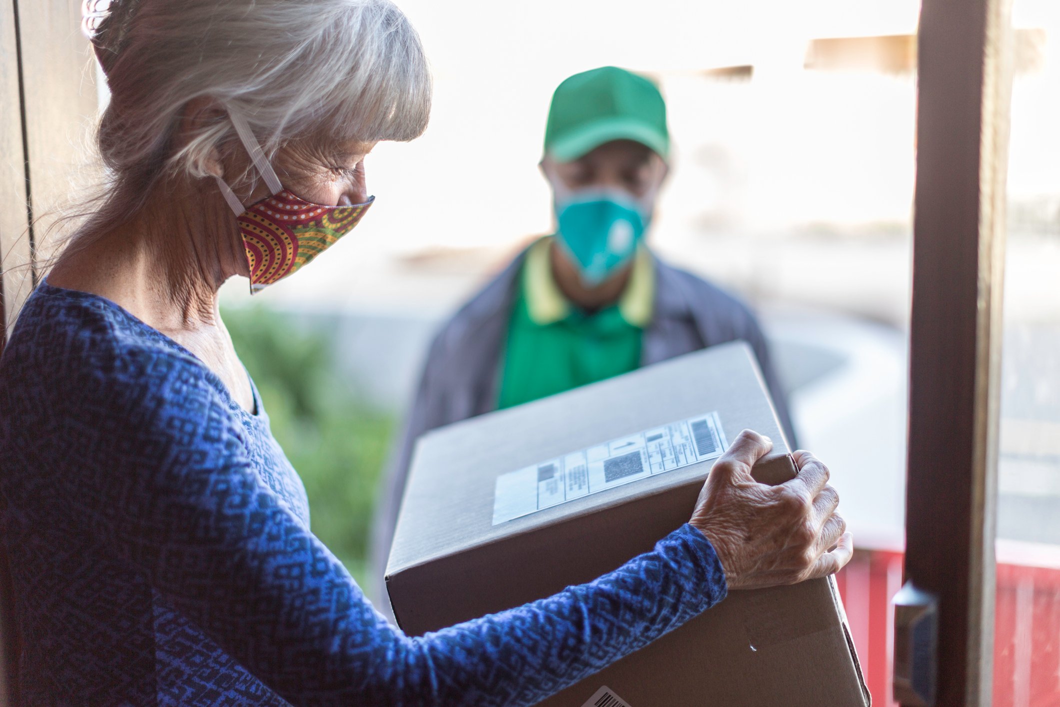 A senior woman looks at a package just delivered to her in her doorway. 
