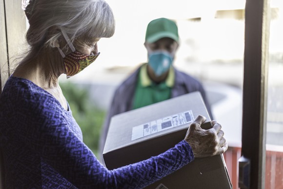 A senior woman looks at a package just delivered to her in her doorway. 
