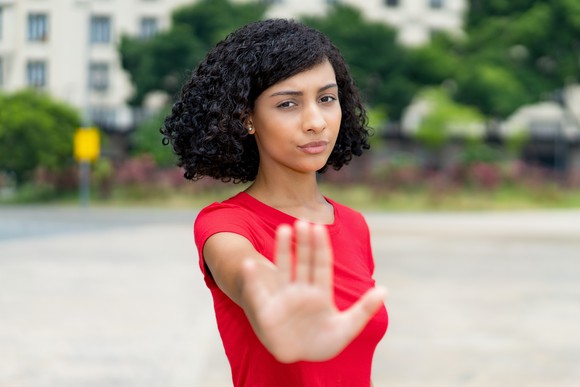 Young woman holding out her hand, halting the observer.
