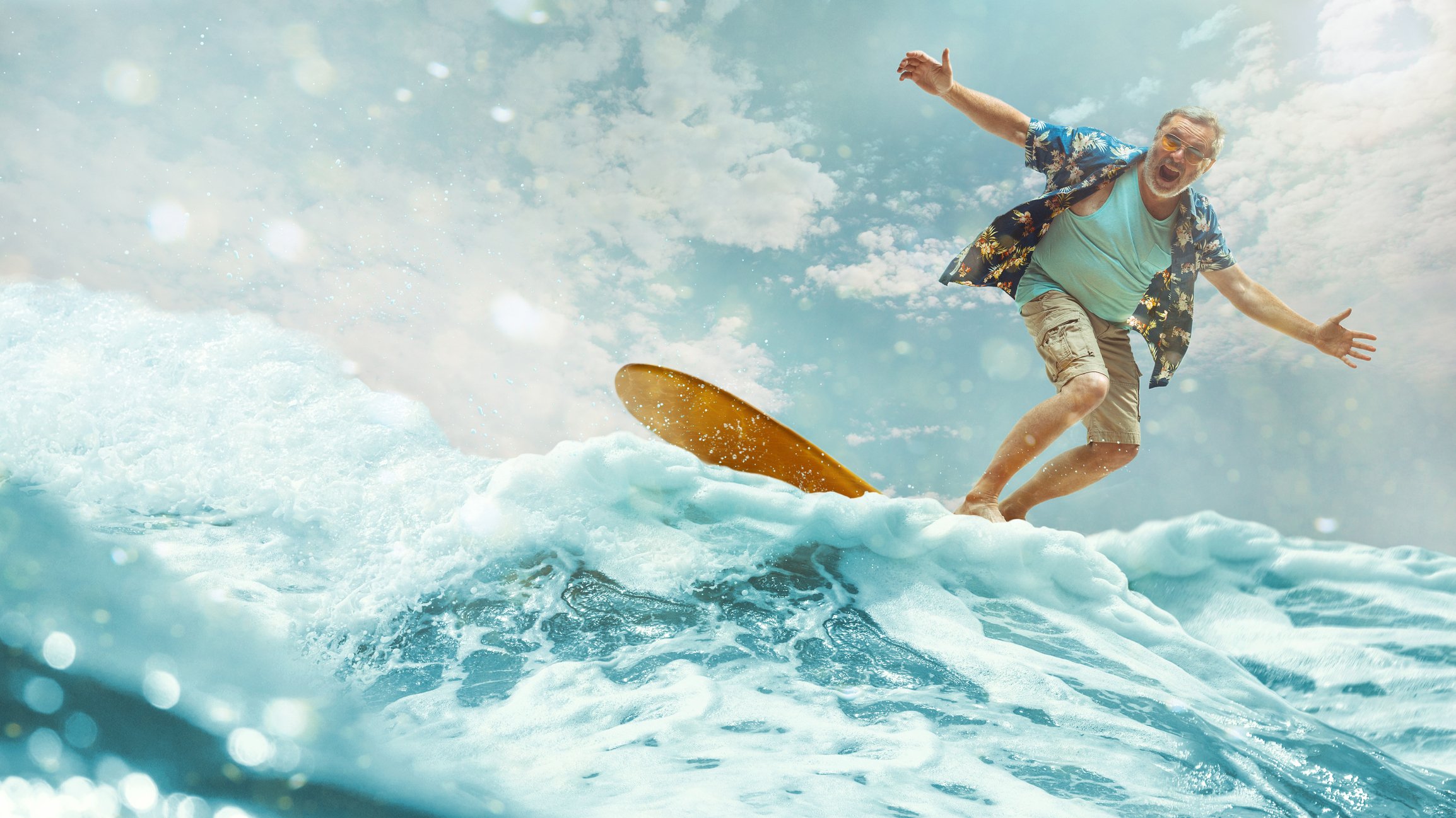 gray haired man riding surfboard in waves
