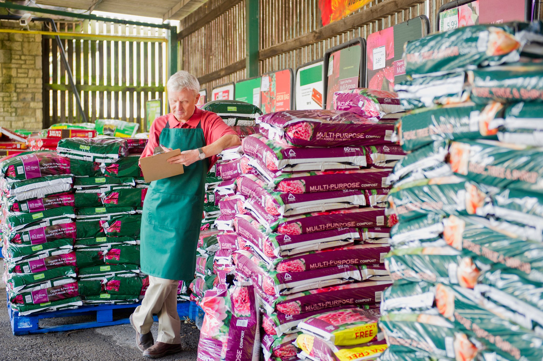 A worker stands near piles of fertilizer in a gardening supply store.