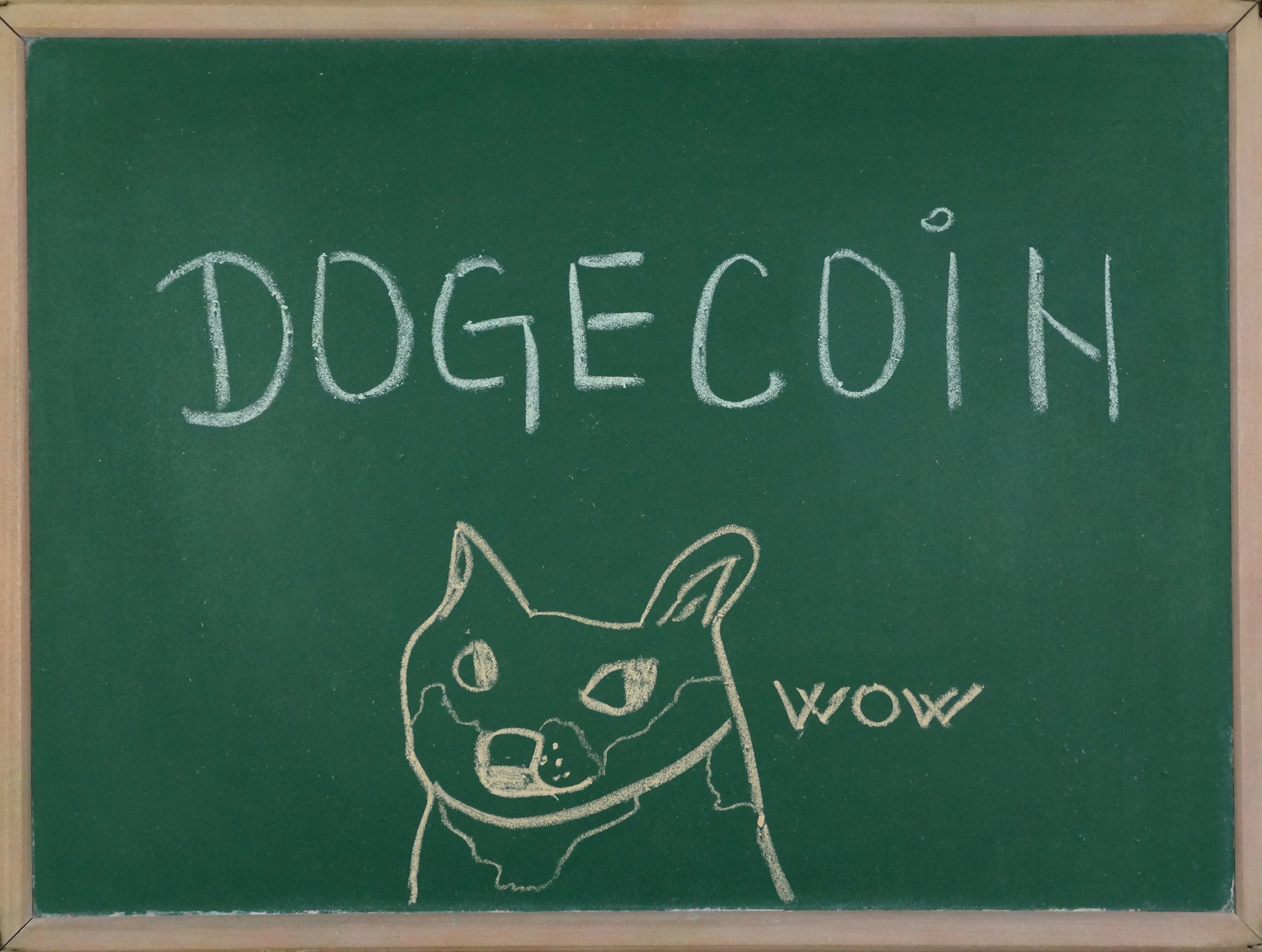 Dogecoin written on a chalkboard with a picture of a dog saying wow.
