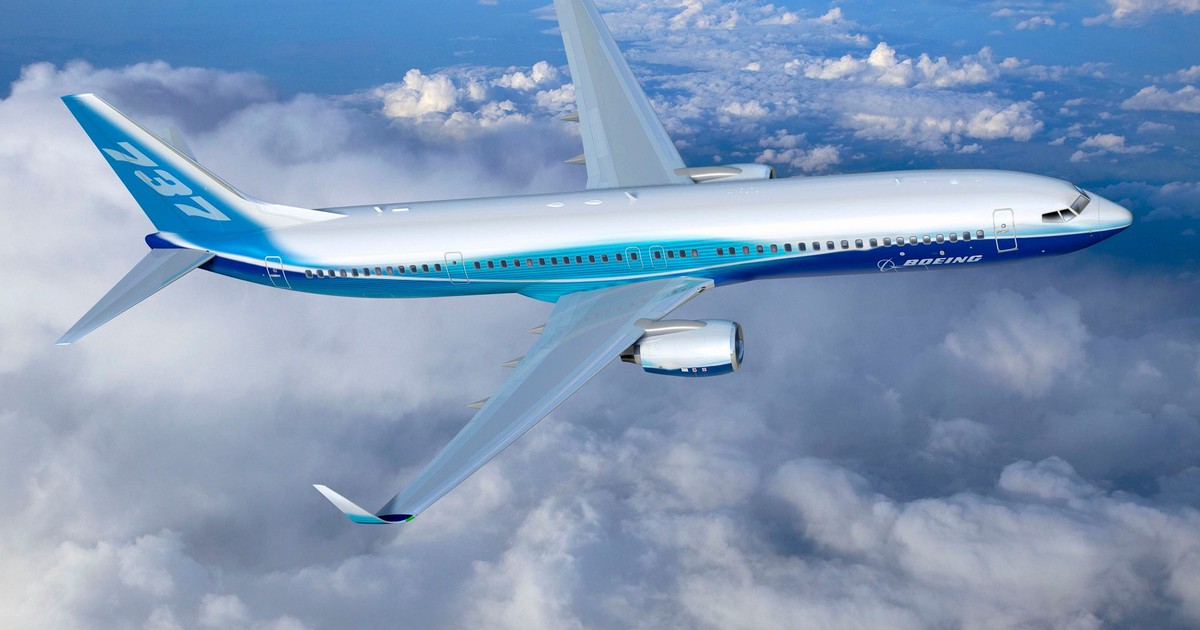 Boeing 737 MAX in the air above some clouds.