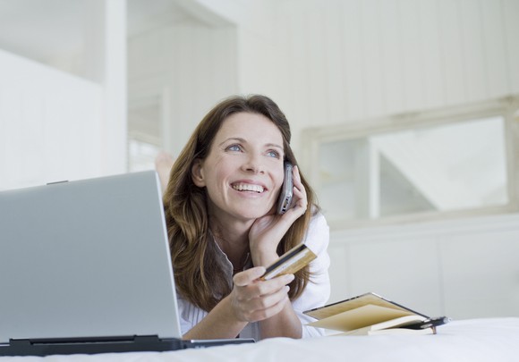 Woman on phone holding credit card.