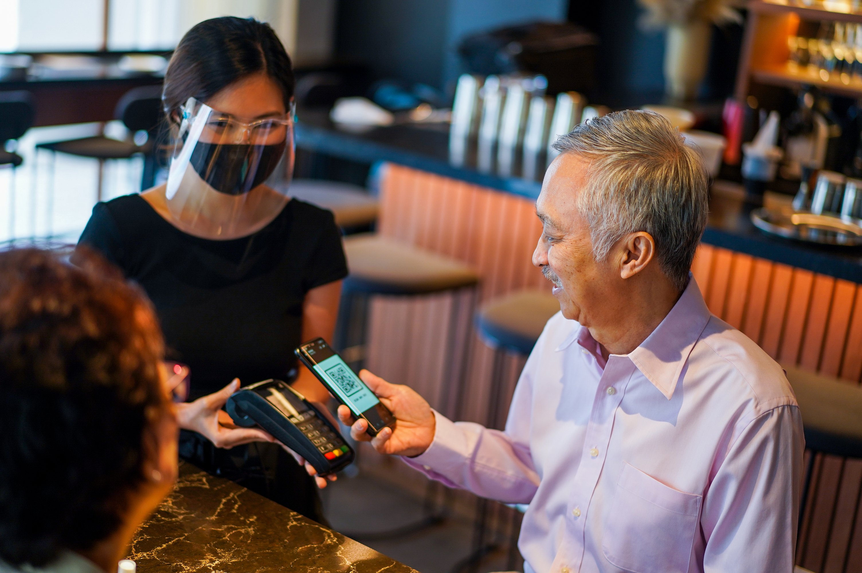 Older couple pay for their meal in a restaurant using a mobile credit card reader.