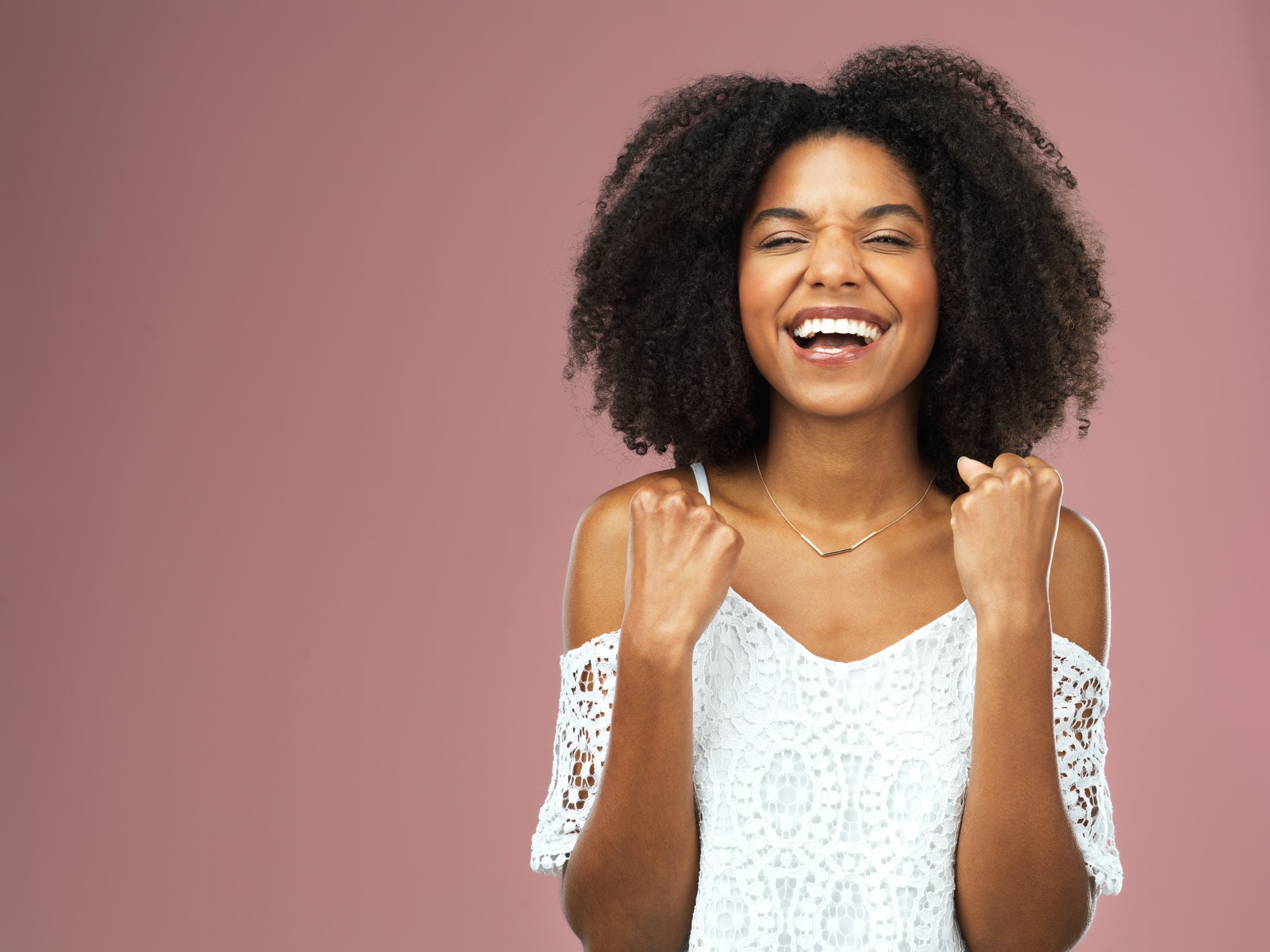 A young woman cheering against a pink background.