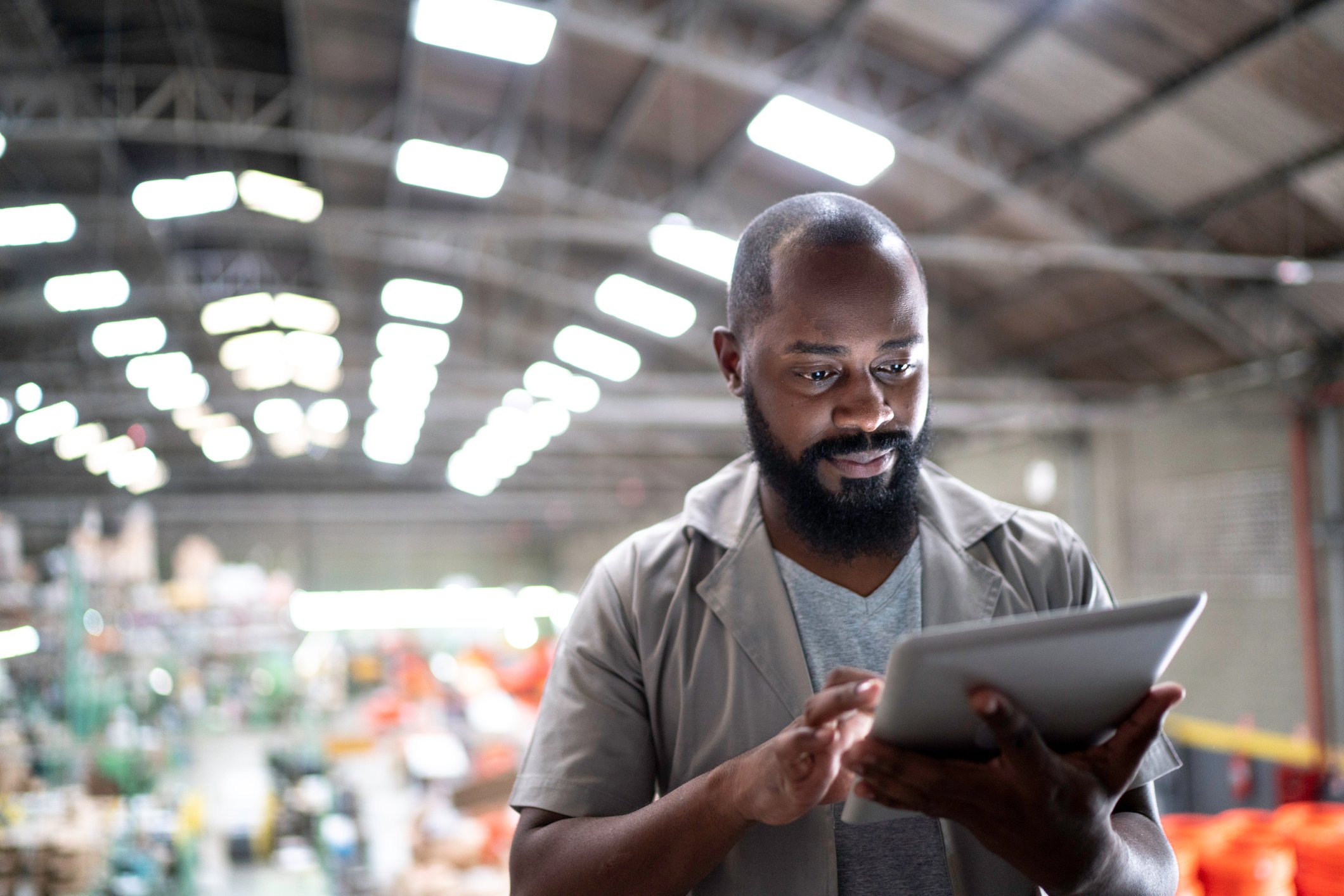 A man using a tablet in an industrial setting.