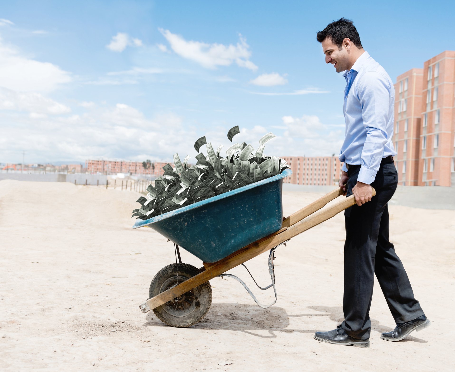 GettyImages-man and wheel barrow of cash