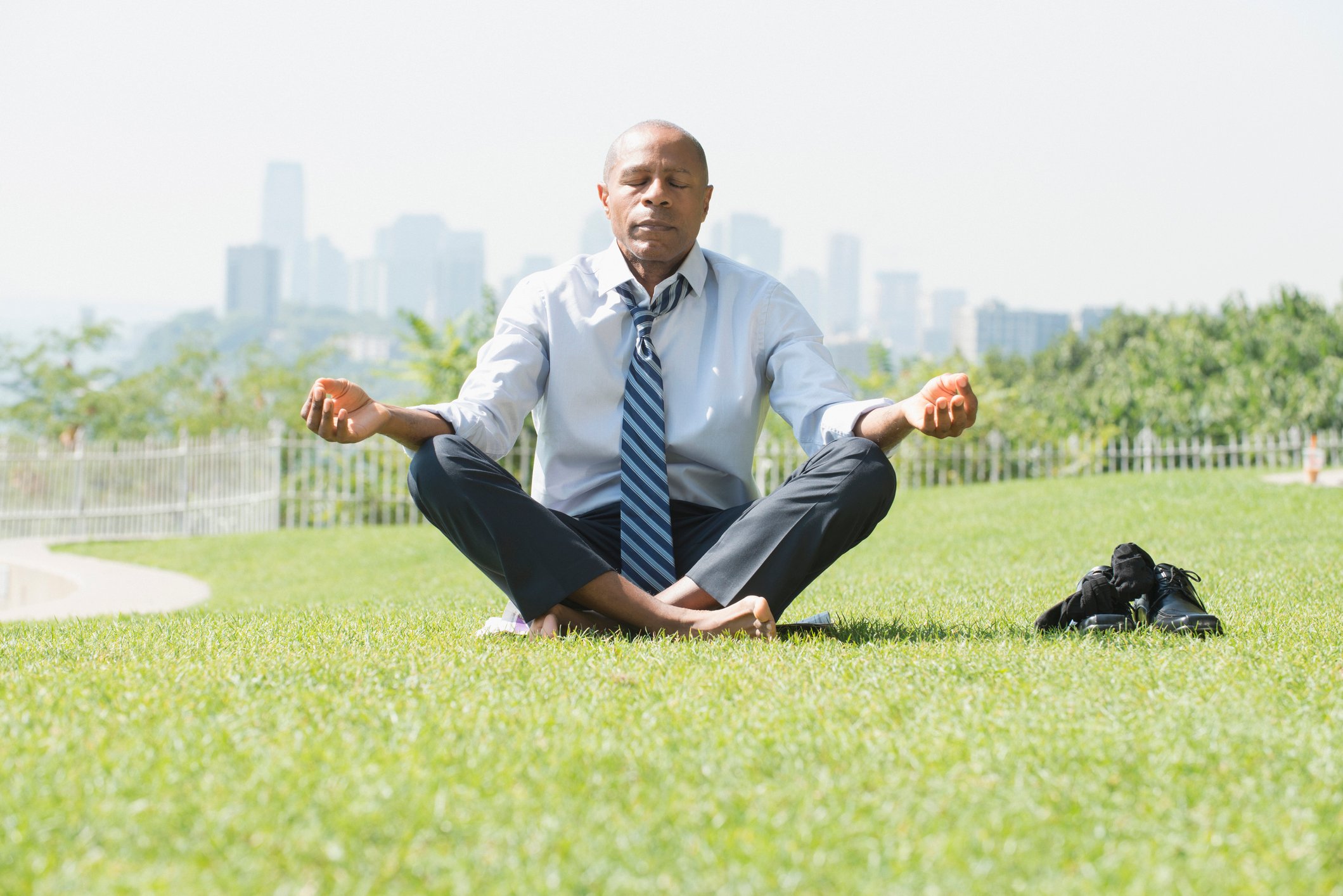 Man in shirt and tie meditating in field