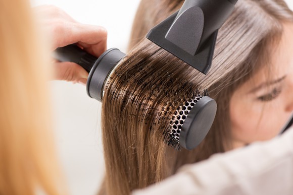 A salon customer having her hair blow-dried.