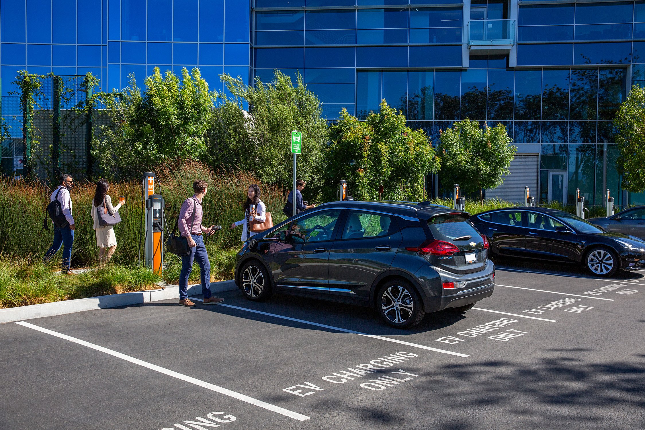 students walking by ChargePoint charging station in parking lot