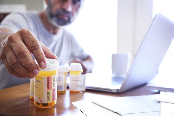 Man reaching for his medication on the dining table. 