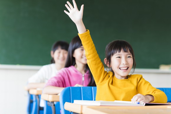 A girl raises her hand in a classroom.