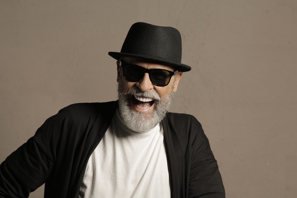 A bearded smiling man wearing sunglasses and a black hat.