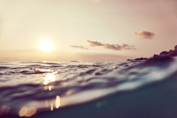 A sun sets over ocean waves. 