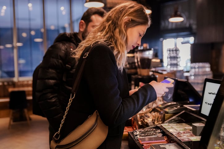 Woman uses her mobile phone to order at a coffee shop.