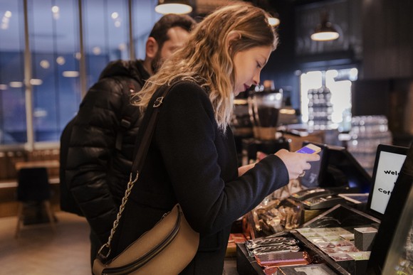 Woman uses her mobile phone to order at a coffee shop.