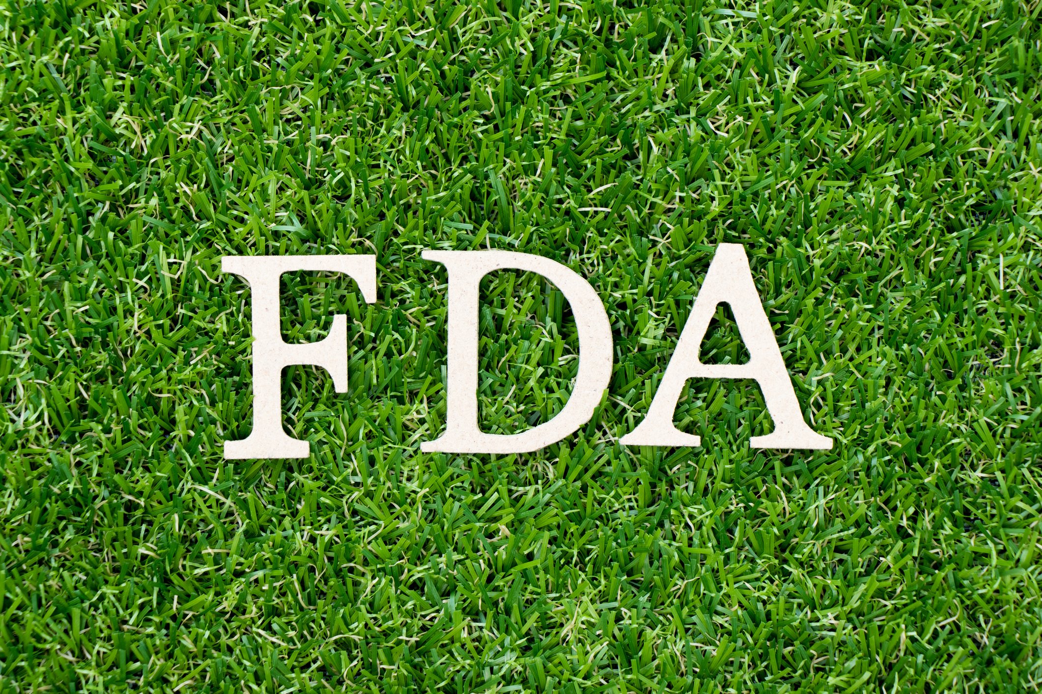 The letters "FDA" are pictured against bright green grass.