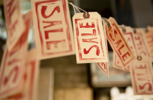 Paper tags hanging from a string with the word sale written on them in red letters.