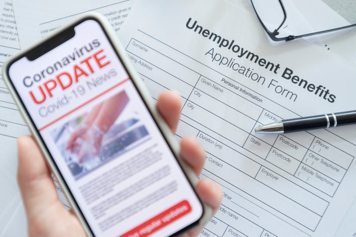 Unemployment benefits application and phone displaying COVID-19 news