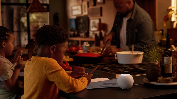 A man and two children in a kitchen, with a HomePod Mini on the counter