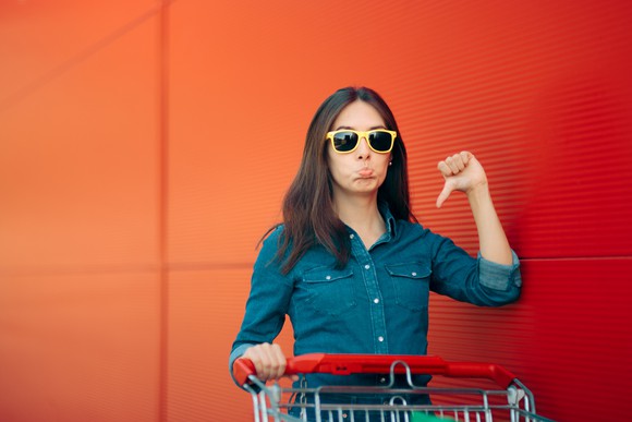 A young woman in sunglasses gives a thumbs down sign.