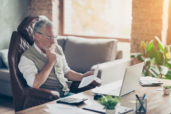 A man sitting at a desk and looking at a piece of paper.