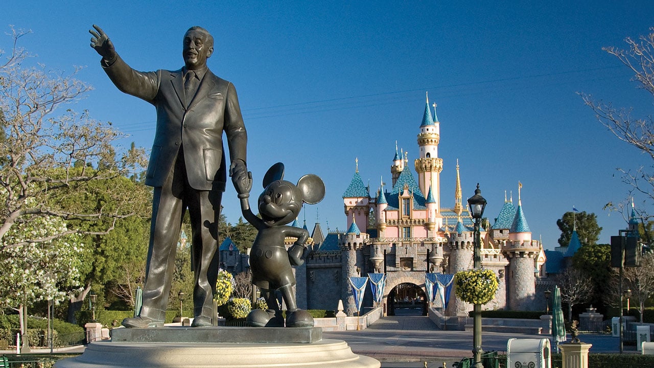 A Walt Disney and Mickey Mouse statue in front of Disneyland's signature castle.