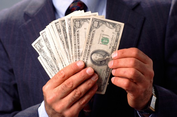 Person in suit counting hundred dollar bills