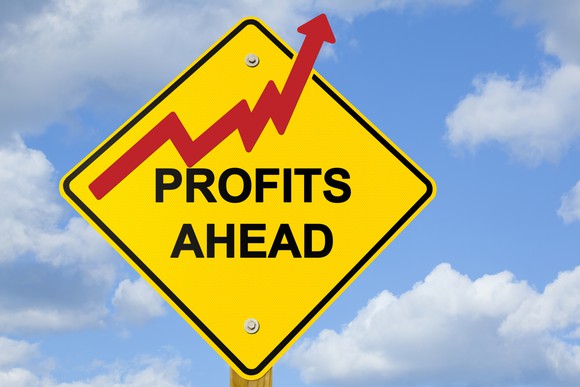 yellow road sign saying profits ahead, with red stock arrow going up