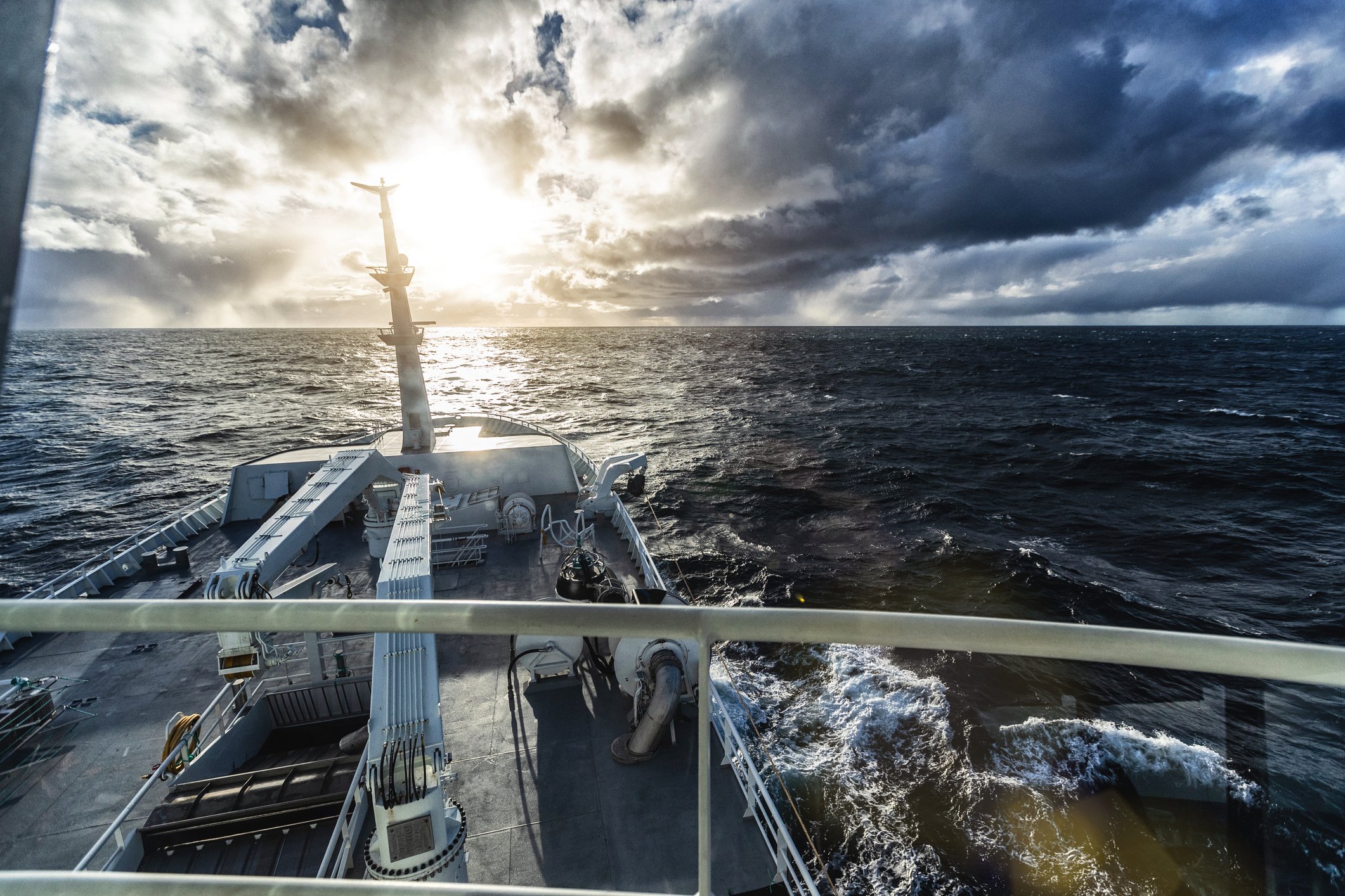 Sun breaking through storm clouds from the perspective of an oceangoing vessel.