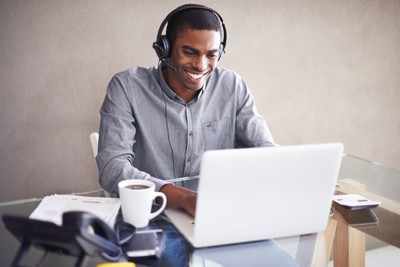 Man wearing headset while using his laptop in a work setting.