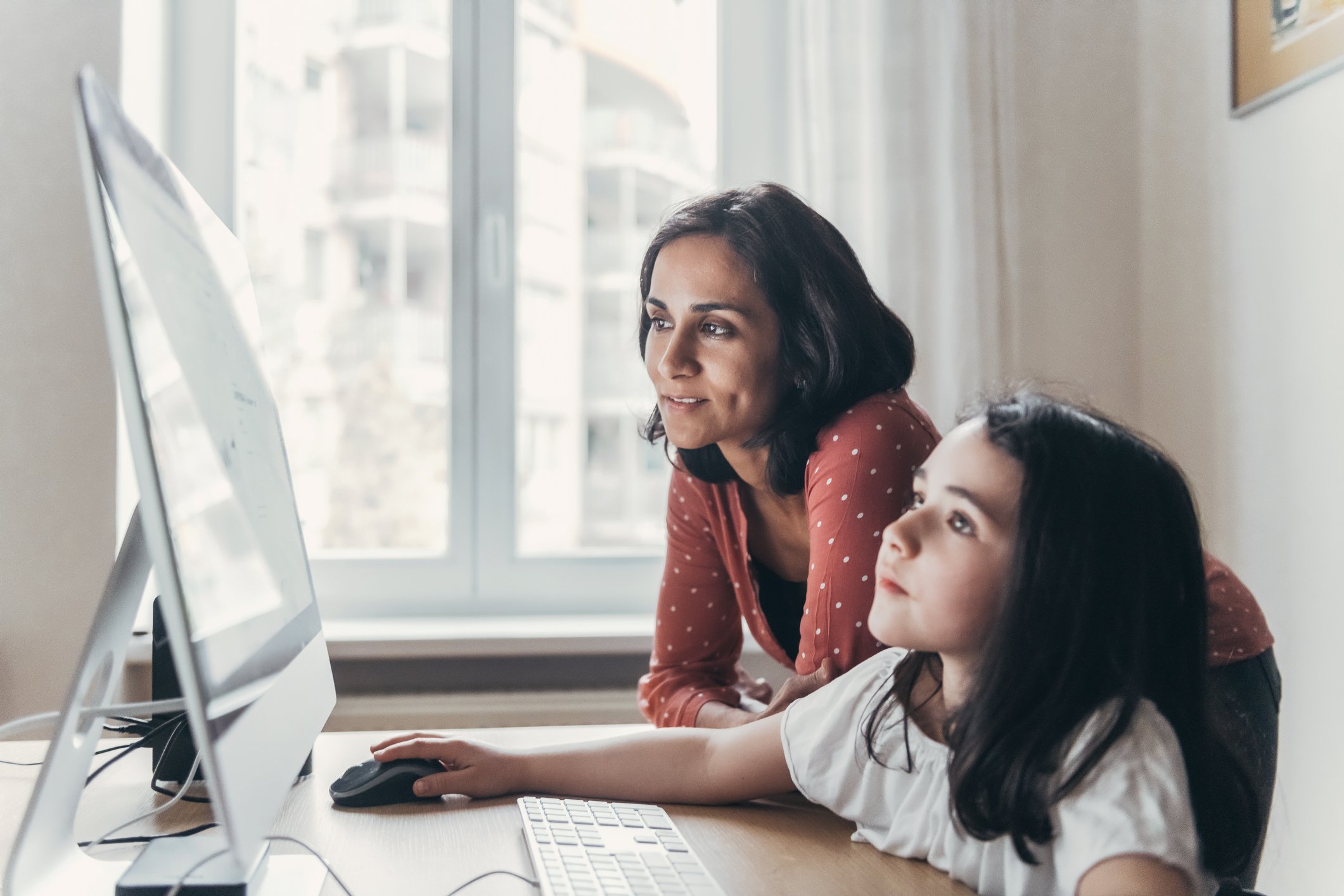 A woman and child use a computer together.