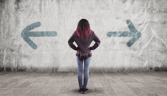 Arrows drawn on a wall pointing left and right with a woman facing the wall with her hands on her hips