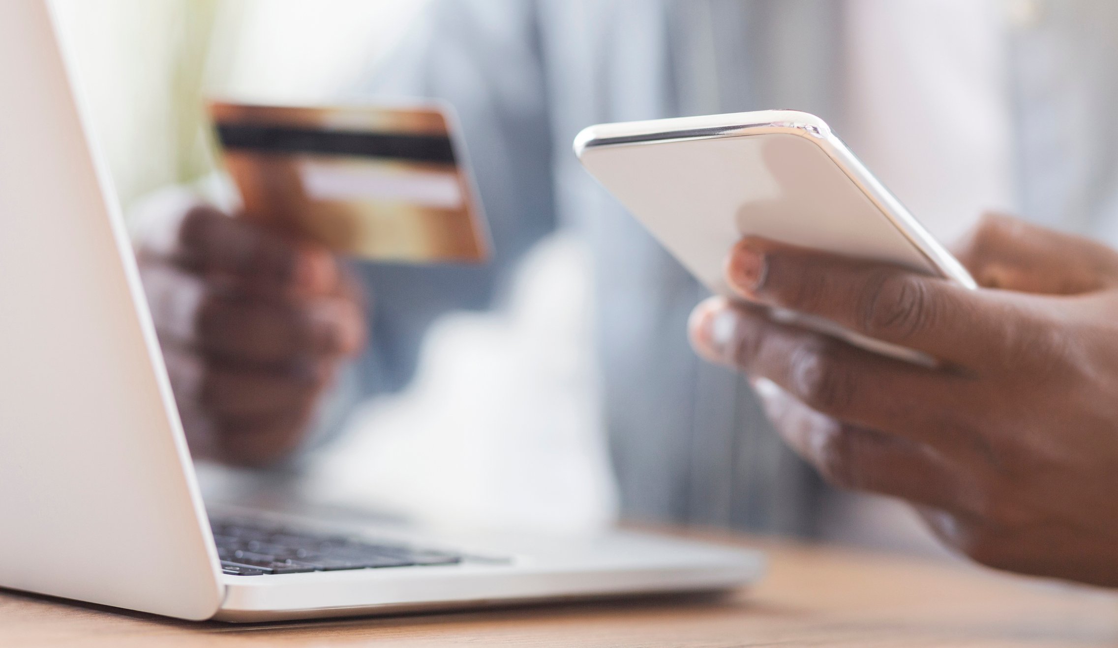 Someone on laptop with smartphone and credit card