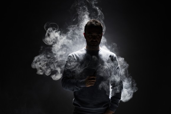 Person smoking an e-cig in a dark room. 