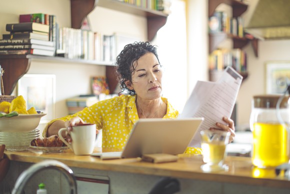 Woman in cafe looking at laptop and papers