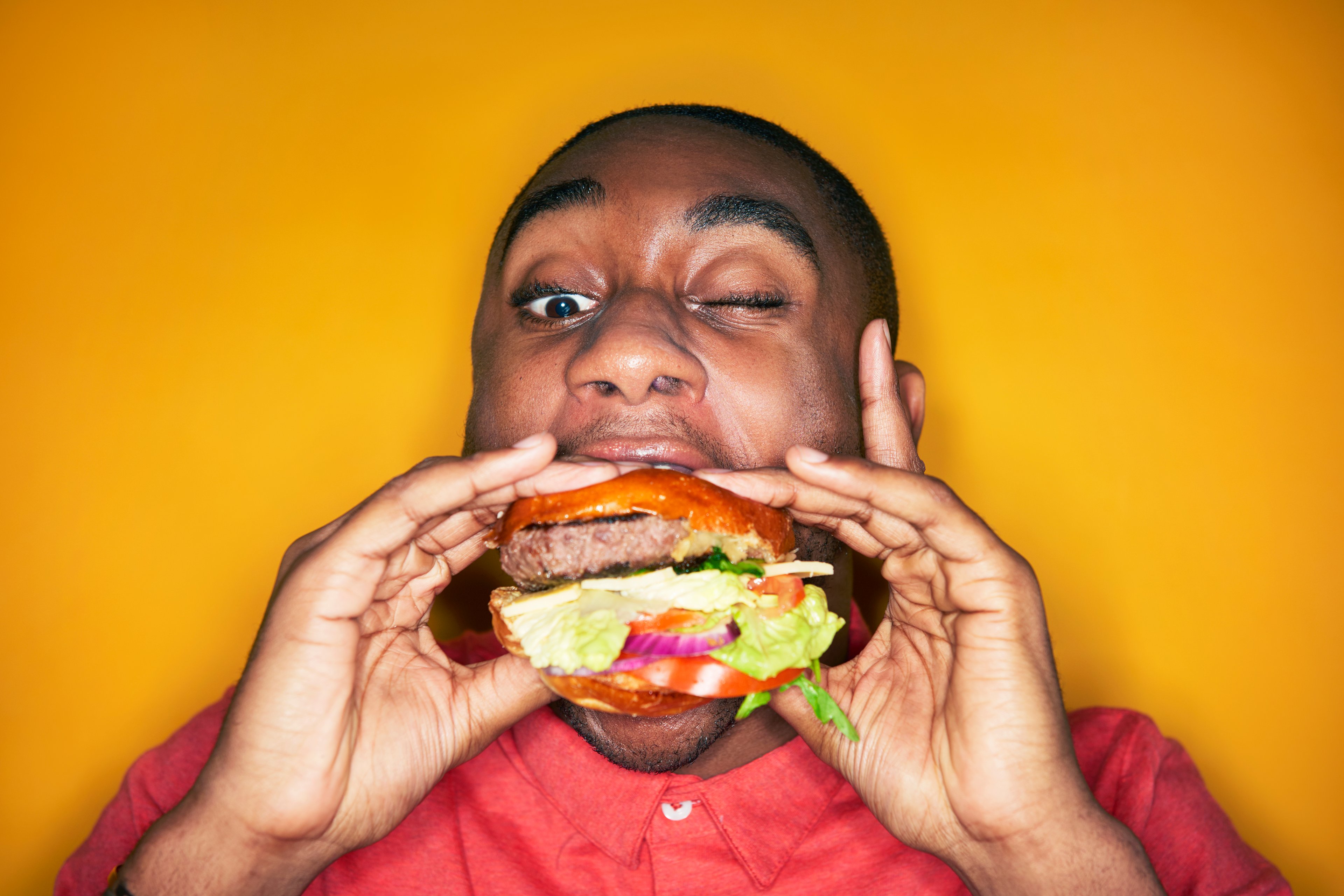 A man taking a bite out of a hamburger.