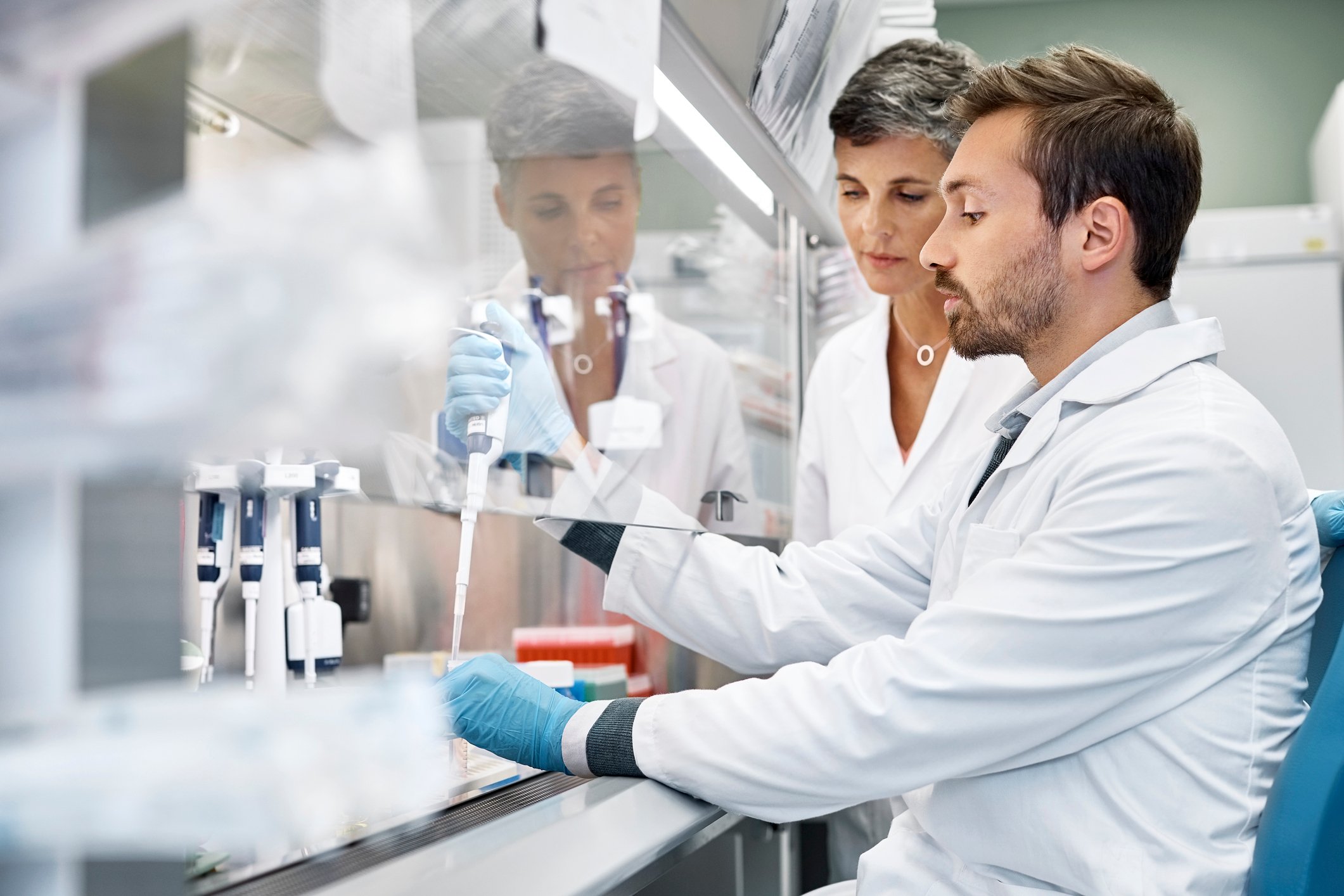 Two workers in a laboratory with pipettes and chemical samples.