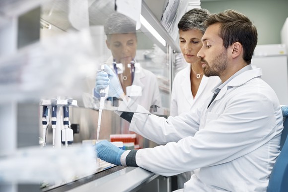 Two workers in a laboratory with pipettes and chemical samples.