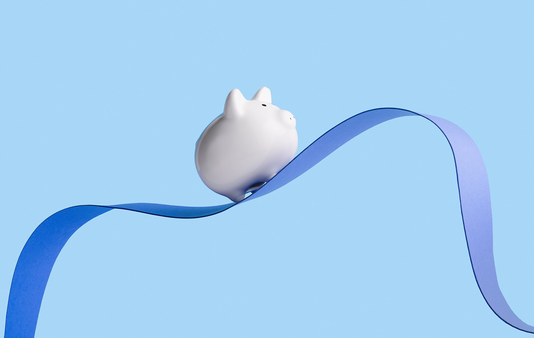 A piggy bank on top of a wavy ribbon.