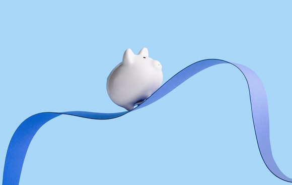 A piggy bank on top of a wavy ribbon.