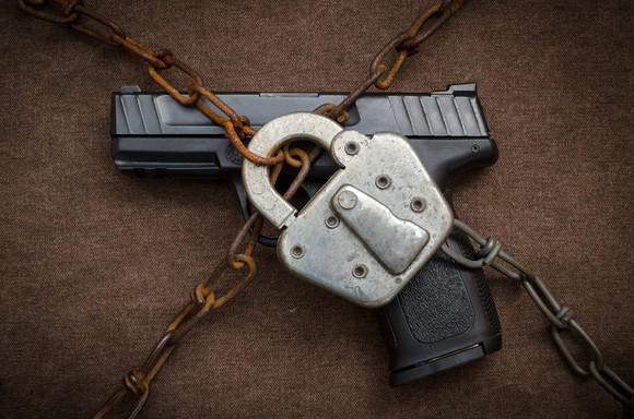 An automatic handgun under a lock and chains.