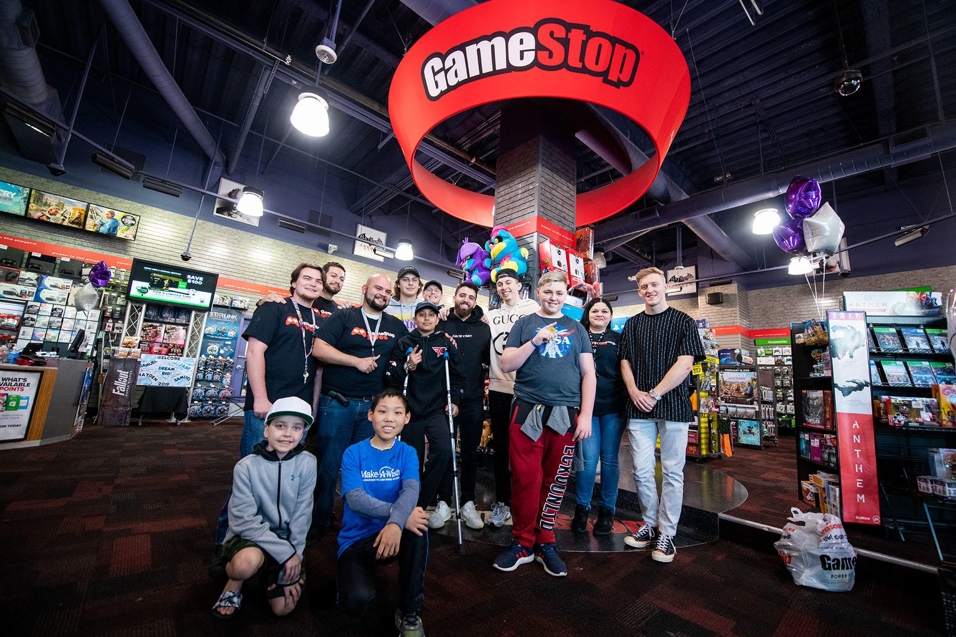 Customers and employees posing at a GameStop store.