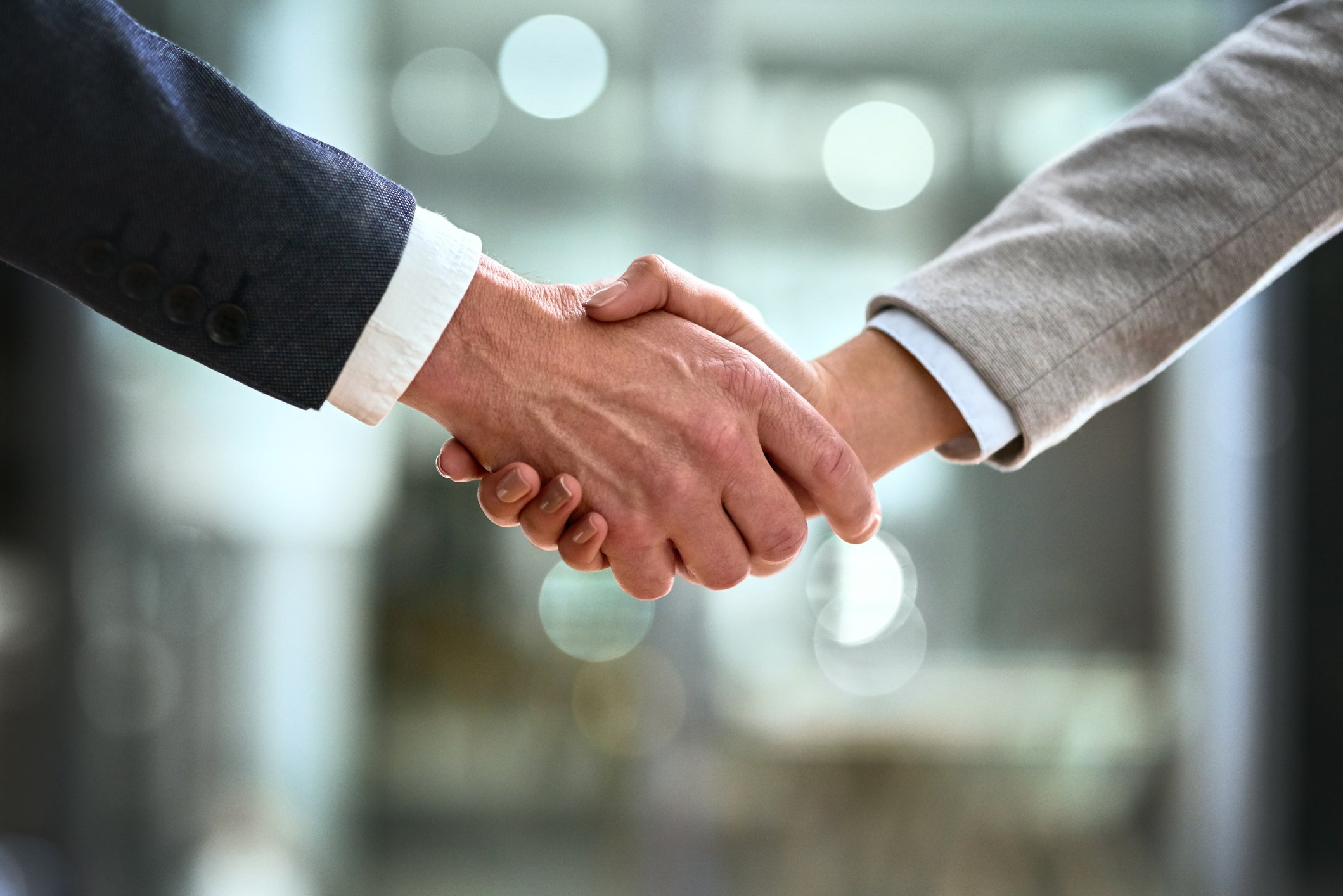 Hands of a businessman and businesswoman shaking hands on a deal.