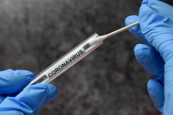 Gloved hands holding a cotton swab and a vial labeled "coronavirus"