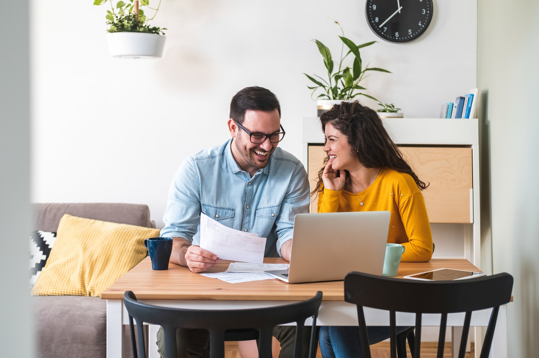 Smiling couple sitting at table reviewing papers