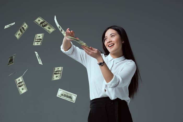 Smiling woman scattering $100 bills.