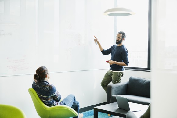 Colleagues discussing ideas on a whiteboard.